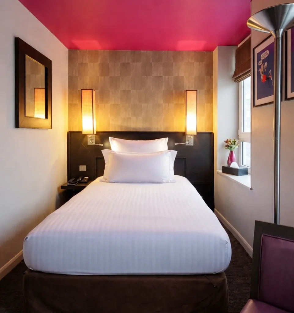 Vue d'ensemble de la chambre single de l'Hotel Aero Paris avec lit en 120 cm, plafond fuchsia et appliques murales